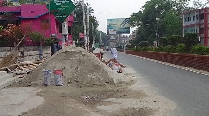 সড়কের অর্ধেক নির্মাণ সামগ্রীর দখলে, ভোগান্তিতে পথচারীরা